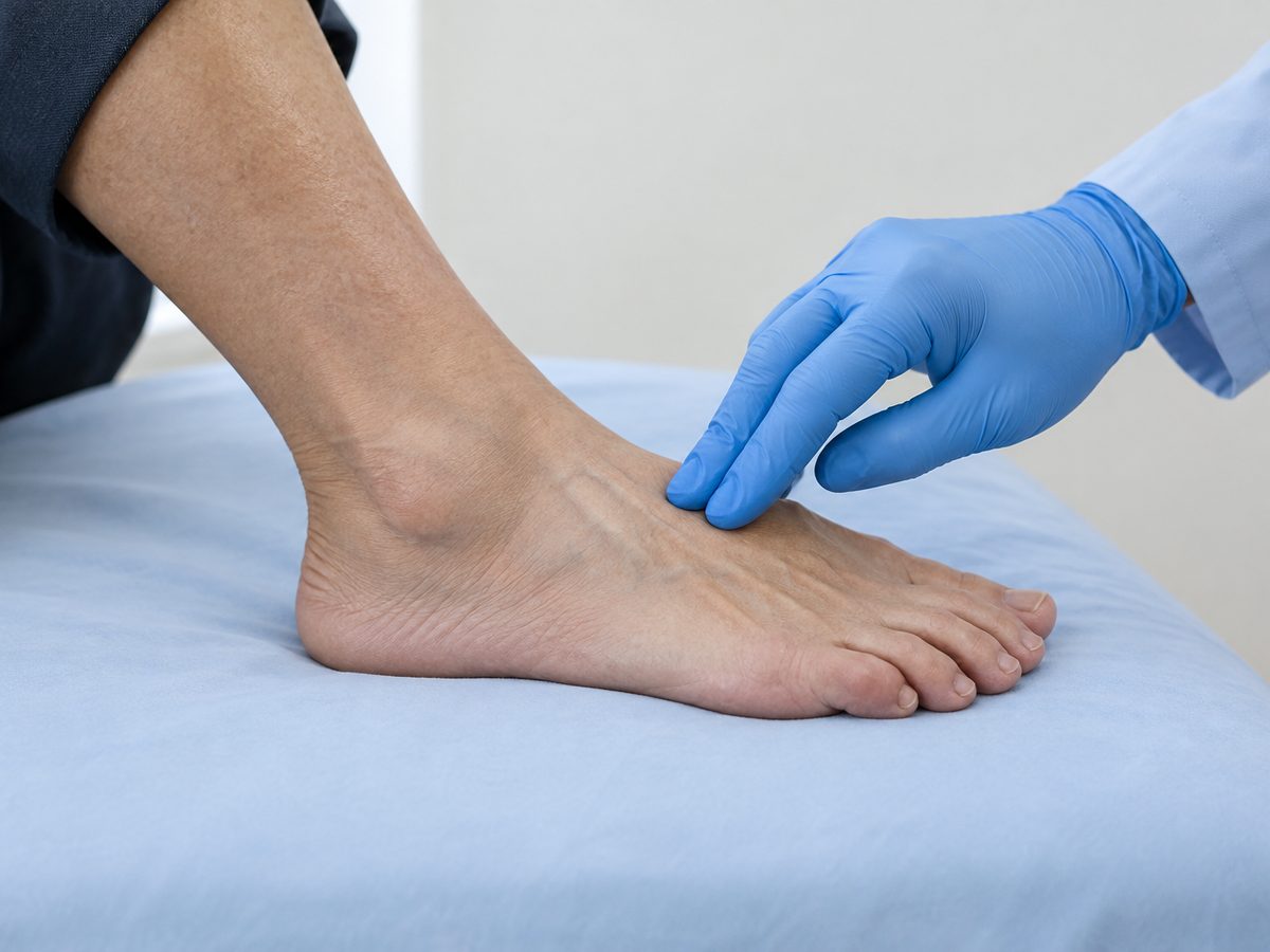 Gloved fingertips feeling for the pulse on the top of a foot