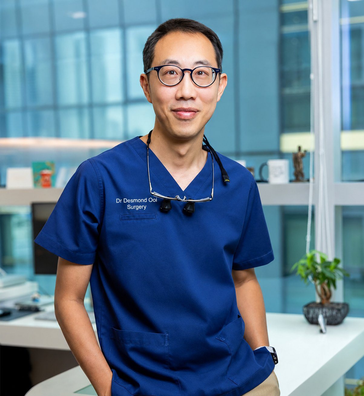 Dr Desmond Ooi in navy scrubs at his clinic desk